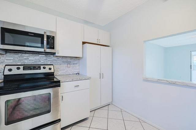 kitchen with light tile patterned floors, stainless steel appliances, white cabinetry, light countertops, and tasteful backsplash