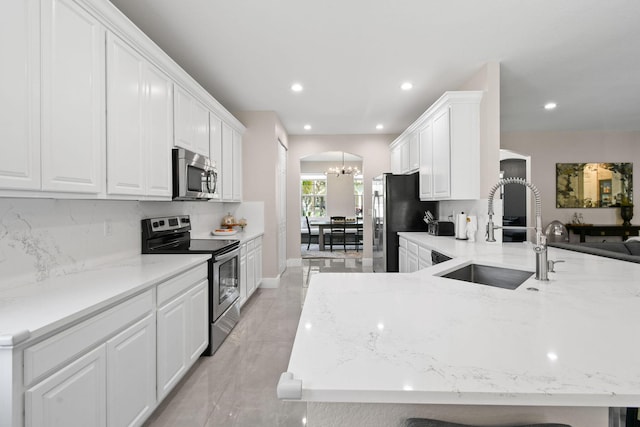 111 Tullamore Ave, Jupiter, FL 33458 - kitchen with appliances with stainless steel finishes, arched walkways, a chandelier, a sink, and white cabinets