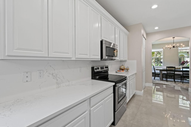 111 Tullamore Ave, Jupiter, FL 33458 - kitchen with appliances with stainless steel finishes, a chandelier, arched walkways, white cabinetry, and decorative backsplash