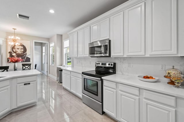 111 Tullamore Ave, Jupiter, FL 33458 - kitchen with stainless steel appliances, backsplash, a chandelier, white cabinetry, and recessed lighting