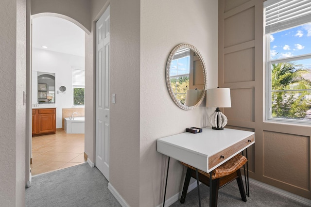 111 Tullamore Ave, Jupiter, FL 33458 - hallway with arched walkways, light colored carpet, a textured wall, and light tile patterned flooring