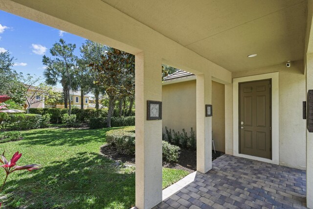 111 Tullamore Ave, Jupiter, FL 33458 - doorway to property featuring a yard, stucco siding, and a patio area