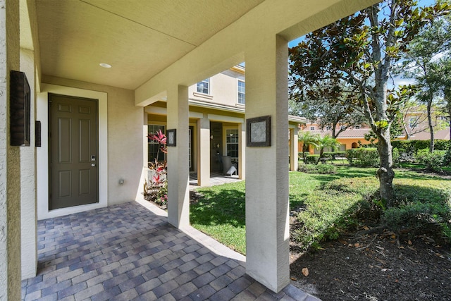 111 Tullamore Ave, Jupiter, FL 33458 - view of exterior entry featuring stucco siding, a patio area, and a lawn