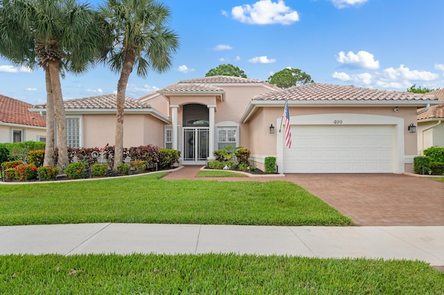 mediterranean / spanish home with stucco siding, decorative driveway, a garage, a front lawn, and a tile roof