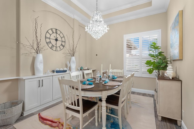 dining space with a chandelier, ornamental molding, wood finished floors, a tray ceiling, and baseboards