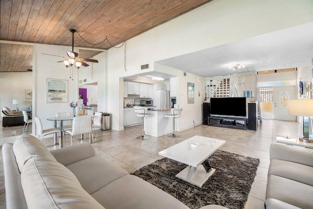 living room with a ceiling fan, wood ceiling, light tile patterned floors, vaulted ceiling, and baseboards