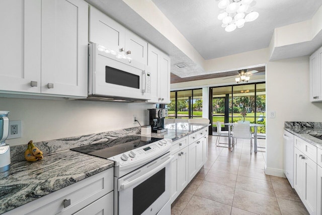 kitchen with white appliances, white cabinets, light stone counters, light tile patterned floors, and baseboards
