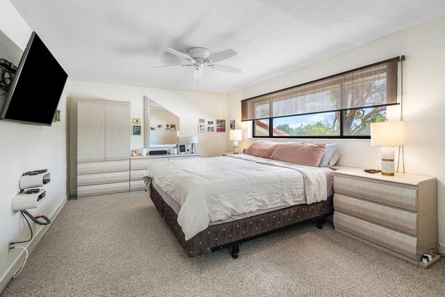bedroom with light carpet, ceiling fan, and a textured ceiling