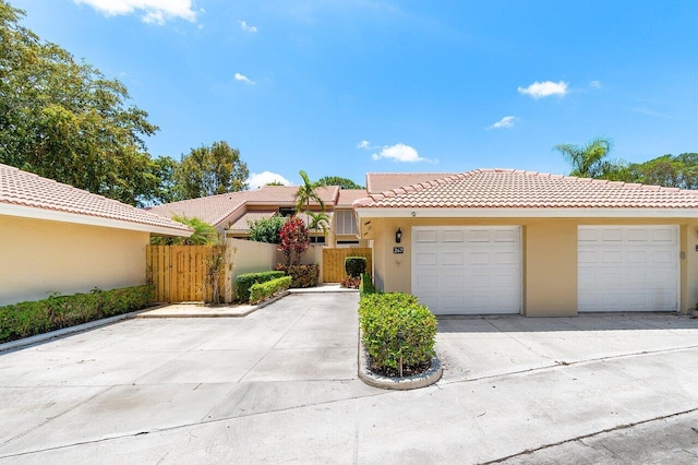 view of front facade featuring stucco siding, a tile roof, fence, concrete driveway, and an attached garage