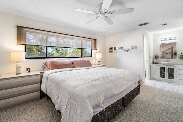 bedroom featuring a textured ceiling, ceiling fan, and ensuite bath