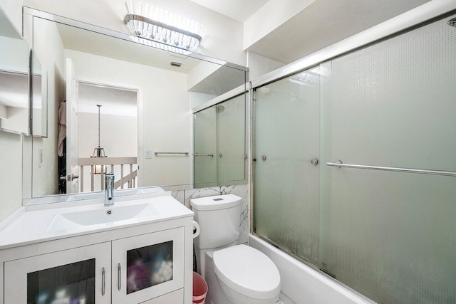 bathroom with toilet, vanity, and combined bath / shower with glass door