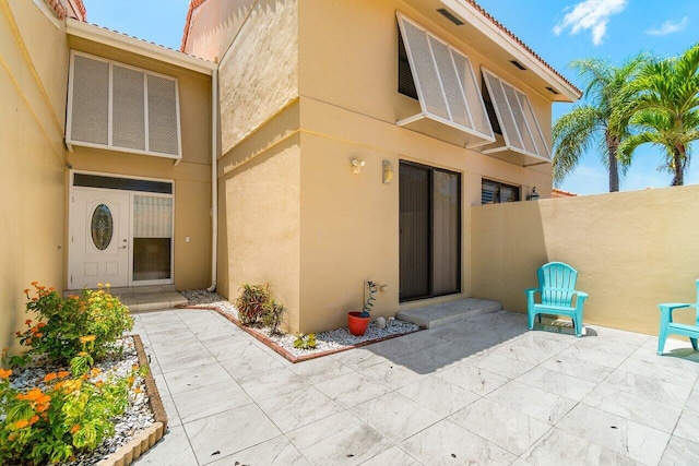 back of house featuring stucco siding, a patio area, fence, and a tiled roof