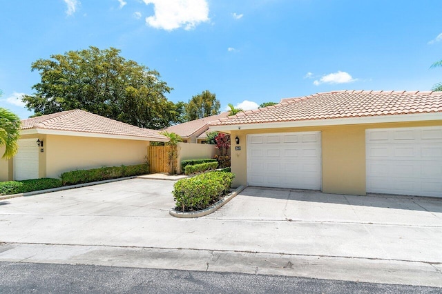 view of front facade featuring a tiled roof, stucco siding, concrete driveway, and fence