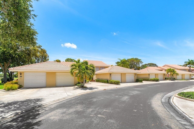 view of front of house with a tile roof, stucco siding, concrete driveway, and an attached garage