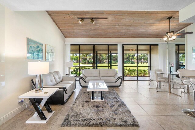 living area featuring wooden ceiling, plenty of natural light, lofted ceiling, baseboards, and tile patterned floors