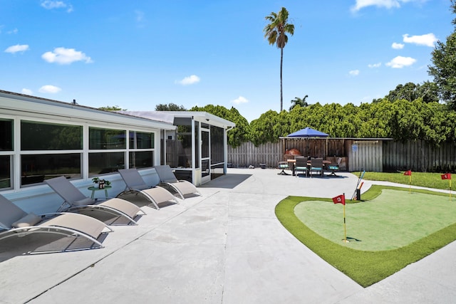 764 Westwind Dr, North Palm Beach, FL 33408 - view of patio / terrace featuring a putting area, a fenced backyard, and a sunroom