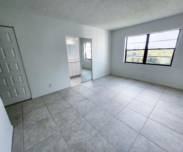 9235 SW 8th St Unit 402, Boca Raton, FL 33428 - spare room with a textured ceiling, light tile patterned floors, and baseboards