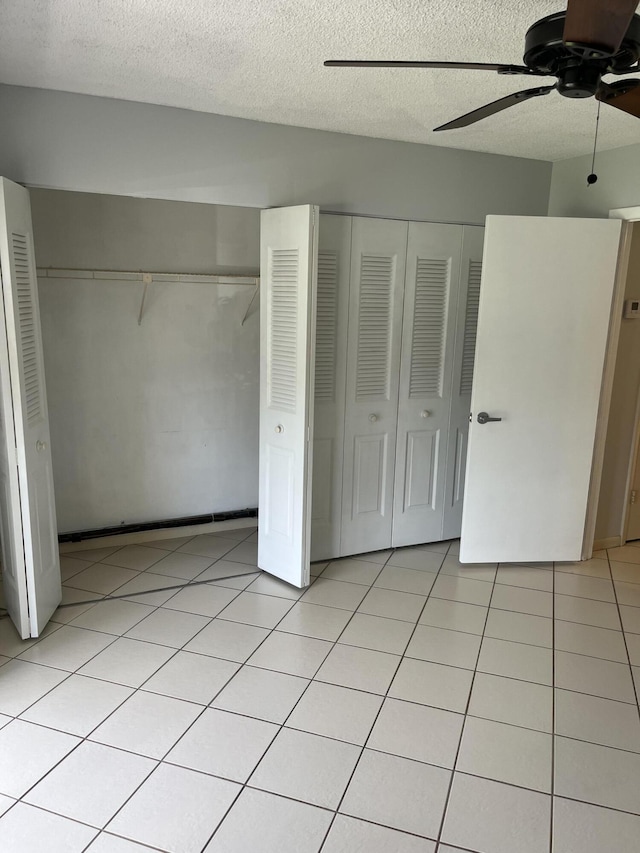 unfurnished bedroom with ceiling fan, a textured ceiling, and multiple closets