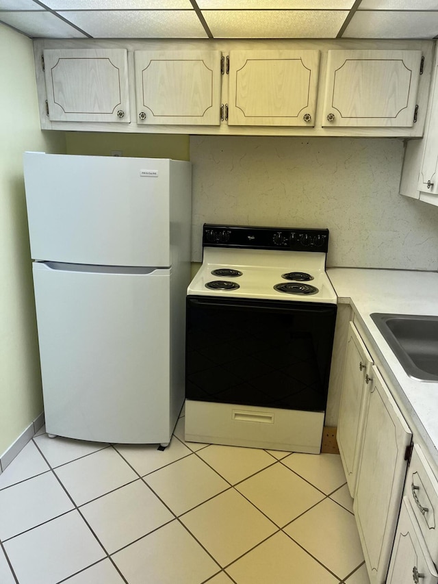 kitchen with freestanding refrigerator, light countertops, a paneled ceiling, and electric range