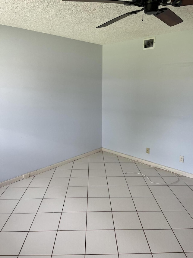 empty room featuring baseboards, ceiling fan, visible vents, and a textured ceiling