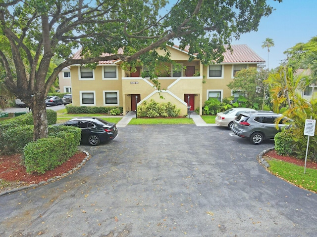 11500 NW 42nd St Unit 1-4, Coral Springs, FL 33065 - view of property with uncovered parking, stucco siding, a tiled roof, and a chimney