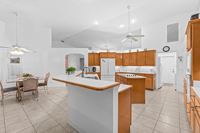 kitchen featuring a kitchen island with sink, white appliances, a ceiling fan, a sink, and light tile patterned floors