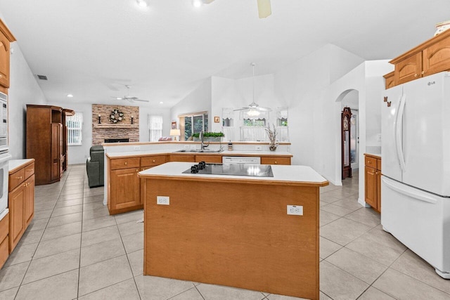 kitchen with freestanding refrigerator, ceiling fan, black electric cooktop, a fireplace, and a kitchen island