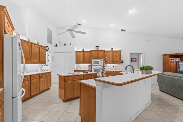 kitchen featuring white appliances, an island with sink, high vaulted ceiling, ceiling fan, and light tile patterned flooring