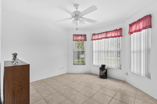 unfurnished room with a ceiling fan, tile patterned floors, and baseboards