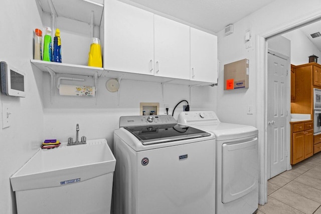 laundry room featuring cabinet space, separate washer and dryer, and light tile patterned floors