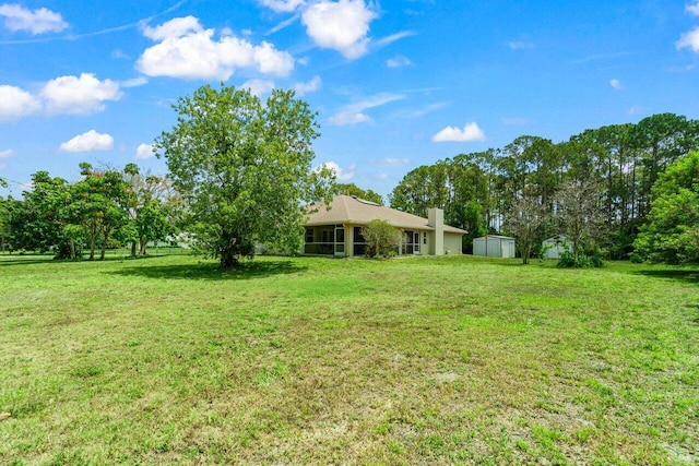 view of grassy yard featuring a storage shed and an outbuilding