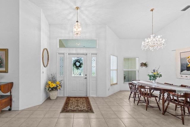 entrance foyer featuring a chandelier, a high ceiling, tile patterned flooring, and baseboards