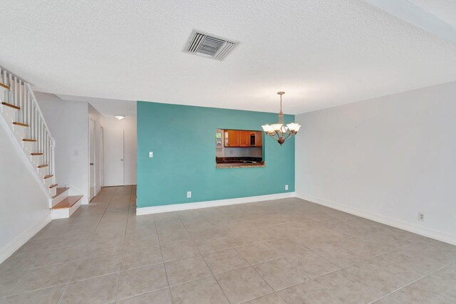 1100 Russell Dr, Highland Beach, FL 33487 - unfurnished room with a chandelier, light tile patterned flooring, stairs, a textured ceiling, and baseboards