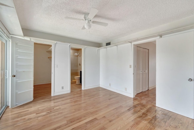 1100 Russell Dr, Highland Beach, FL 33487 - unfurnished bedroom with a textured ceiling, light wood finished floors, a walk in closet, a closet, and ensuite bath