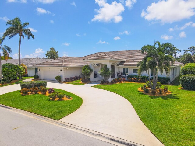 391 Glenbrook Dr, Atlantis, FL 33462 - view of front of house featuring curved driveway, stucco siding, a front lawn, and an attached garage
