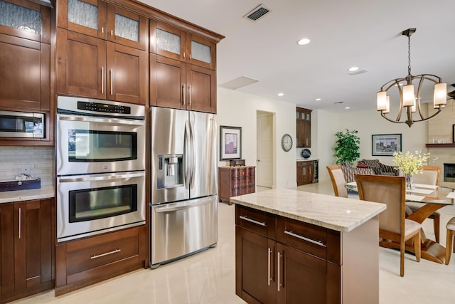 391 Glenbrook Dr, Atlantis, FL 33462 - kitchen with stainless steel appliances, backsplash, a chandelier, light stone counters, and decorative light fixtures