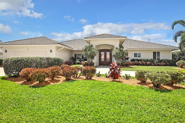 391 Glenbrook Dr, Atlantis, FL 33462 - view of front of property with an attached garage, a front yard, stucco siding, french doors, and a tile roof