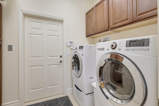 391 Glenbrook Dr, Atlantis, FL 33462 - clothes washing area featuring washing machine and clothes dryer, cabinet space, and light tile patterned floors