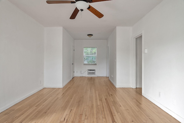 unfurnished room with a ceiling fan, light wood finished floors, heating unit, and baseboards