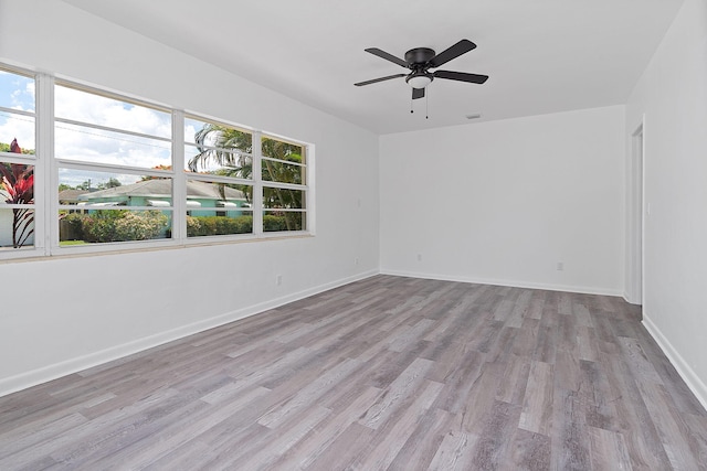 empty room featuring wood finished floors, a ceiling fan, and baseboards