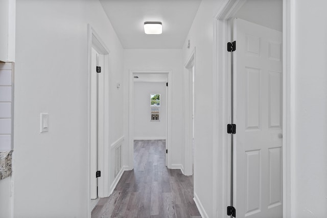 hallway with dark wood-style flooring and baseboards