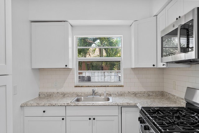 kitchen featuring appliances with stainless steel finishes, a sink, and white cabinets