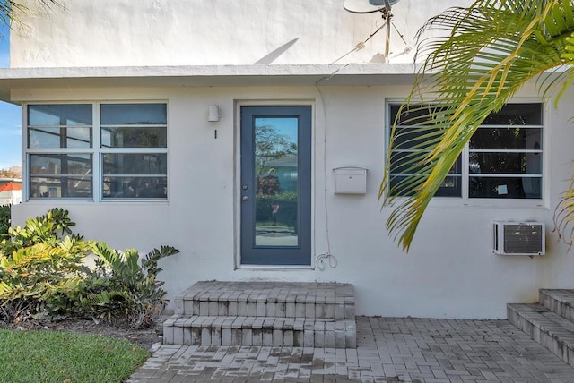 view of exterior entry featuring stucco siding and an AC wall unit