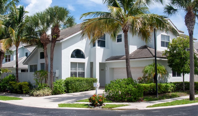 view of front facade featuring stucco siding, a garage, and fence