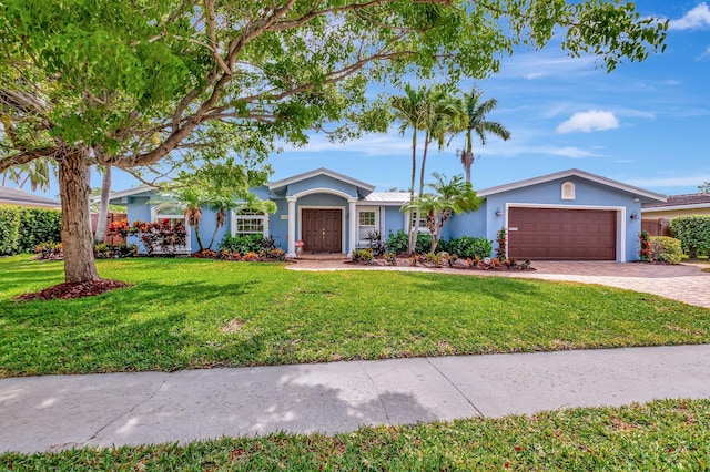 single story home featuring a garage, stucco siding, driveway, and a front yard