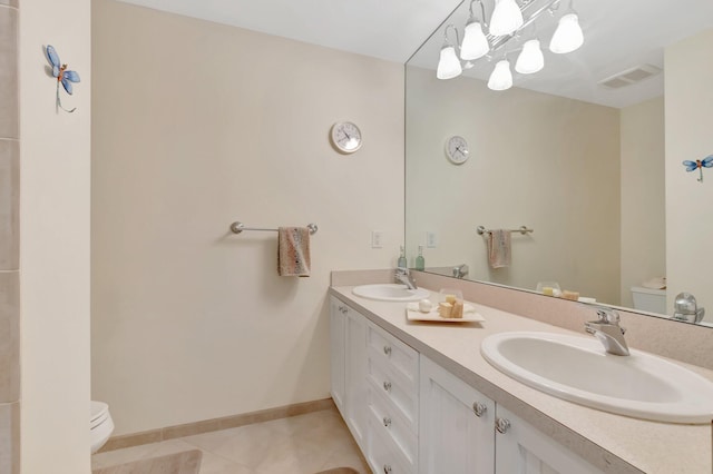 bathroom featuring toilet, tile patterned flooring, double vanity, and baseboards