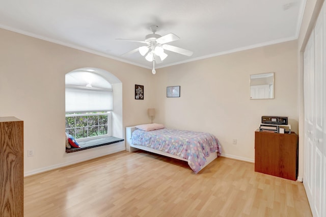 bedroom featuring light wood-style flooring, ornamental molding, arched walkways, baseboards, and ceiling fan