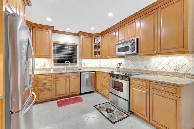 kitchen featuring stainless steel appliances, a sink, light stone countertops, tasteful backsplash, and light tile patterned floors