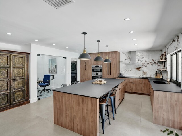2708 NW 26th Cir, Boca Raton, FL 33431 - kitchen with estacked washer and dryer, dark countertops, a sink, modern cabinets, and a kitchen bar