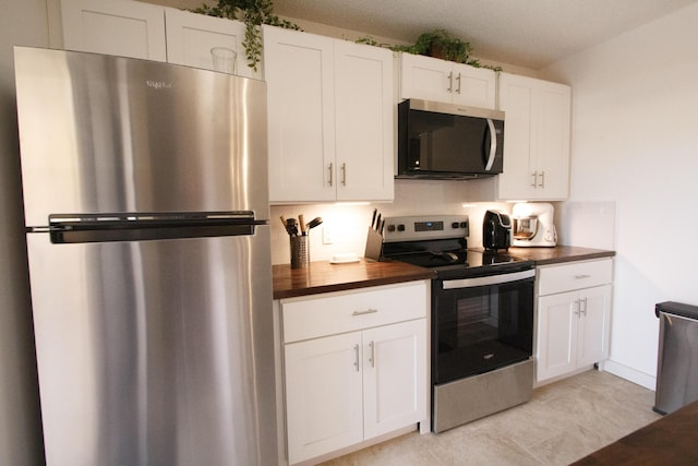kitchen featuring white cabinetry, stainless steel appliances, and butcher block countertops